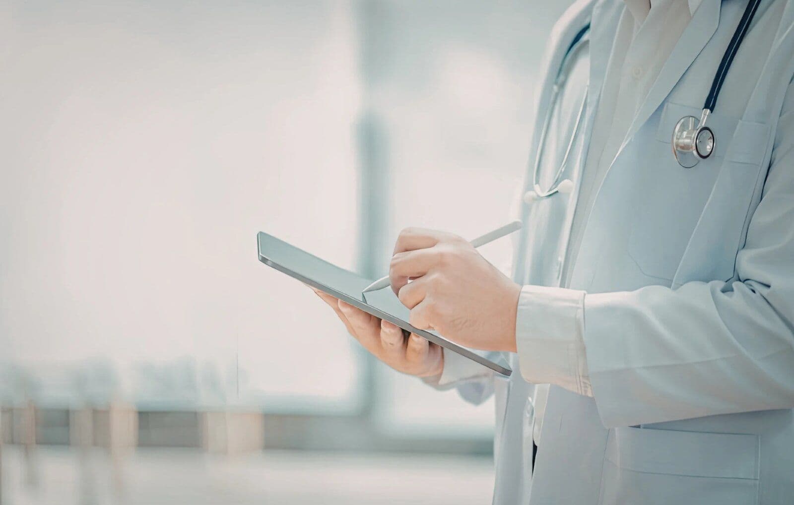 Professionnel de santé en blouse blanche saisissant des données sur une tablette numérique